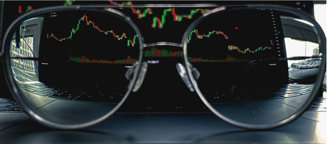 Glasses on laptop with view of trading charts
